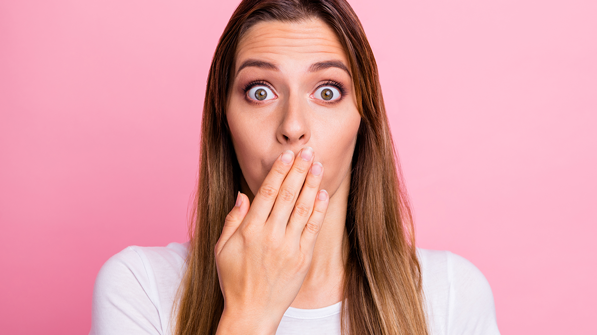 A woman covering her mouth with her hands because she is embarrassed about her missing teeth